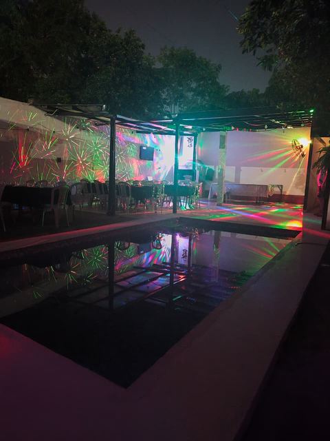 Ambiente nocturno del quincho con luces de fiesta reflejadas en la pileta