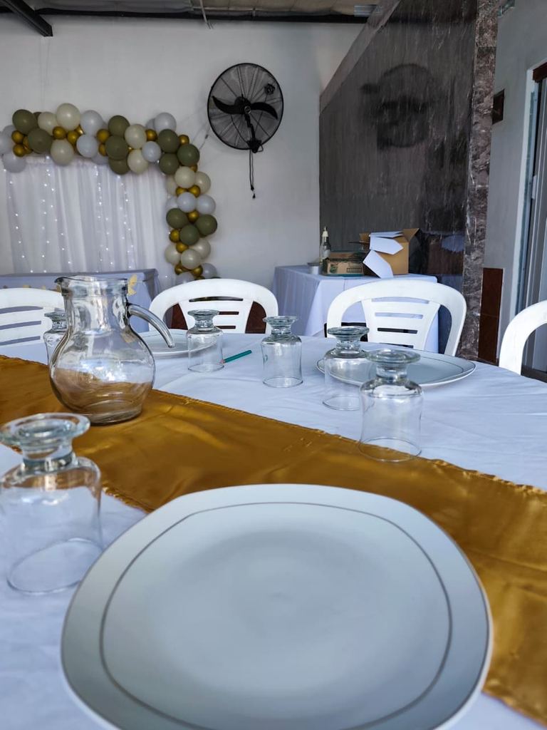 Mesa montada con vajilla y decoración para un evento en el quincho